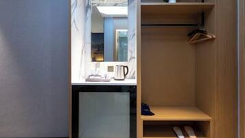 A modern bathroom with a marble vanity, a mirror, a coffee maker, and a wooden shelf with a hanger.