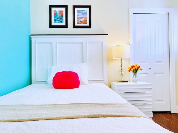 A neatly arranged bedroom with a bed, a bedside table with a lamp, and a door.