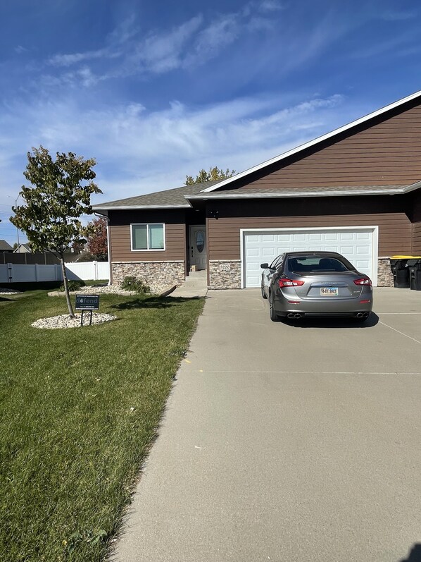 A two-story house with a garage, a driveway, and a tree in the front yard.