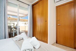 Quarto de hotel com uma cama, guarda-roupa de madeira e porta de correr de vidro que dá para uma área externa.