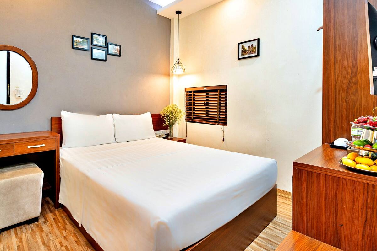 A neatly arranged hotel room with a bed, bedside table, and a small seating area.
