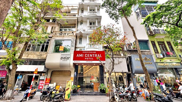 Un hôtel reconnaissable à son grand panneau rouge, avec de nombreux étages et un magasin situé au rez-de-chaussée.