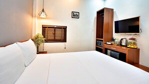 Une chambre d’hôtel comprenant un lit, un bureau avec un téléviseur à écran plat, une machine à café et une petite kitchenette.