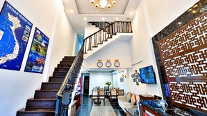 Un hall d’hôtel moderne avec un escalier, un comptoir d’accueil et un mur orné d’un panneau décoratif.