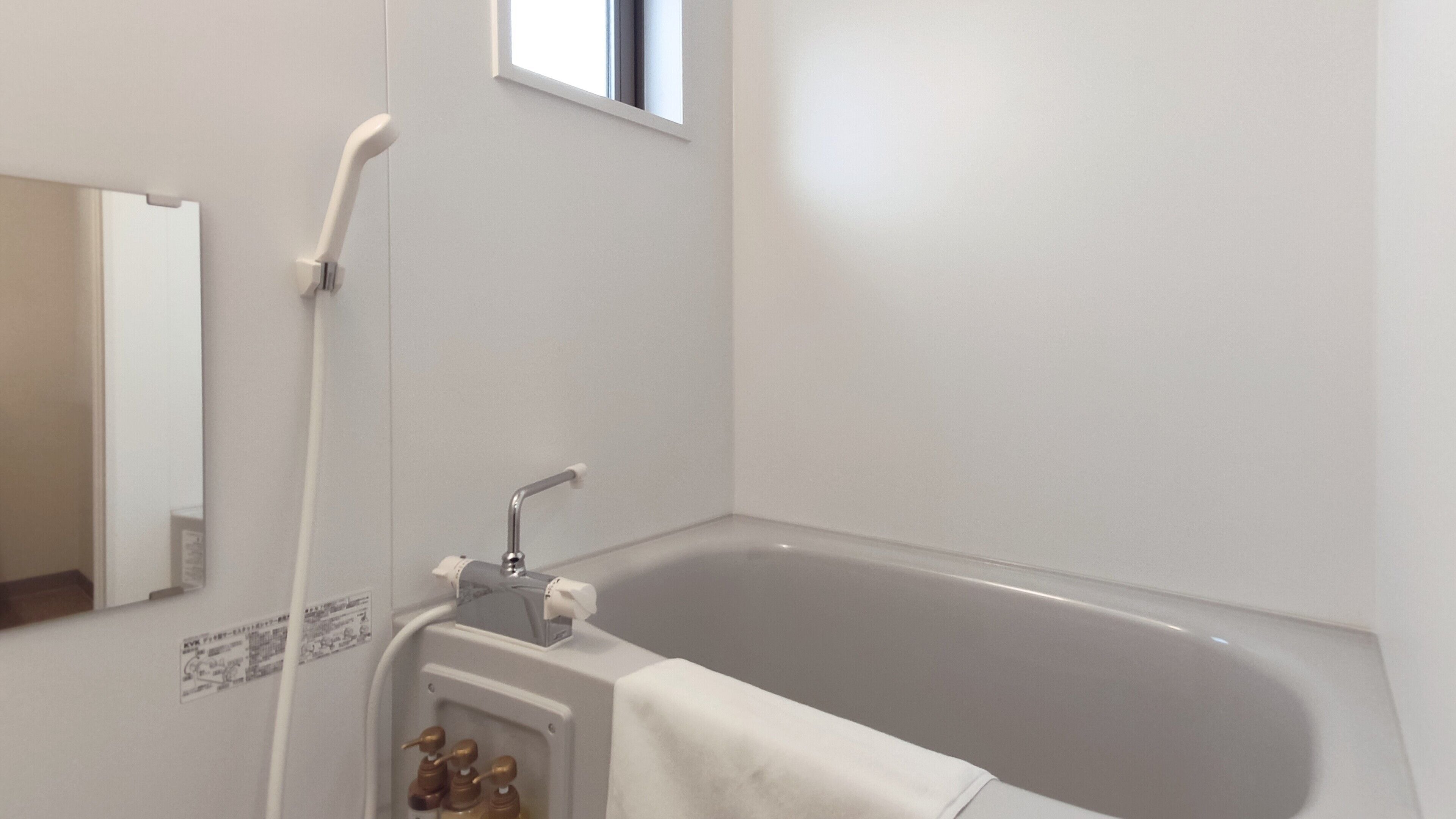 A bathroom with a bathtub, a shower, and a mirror.