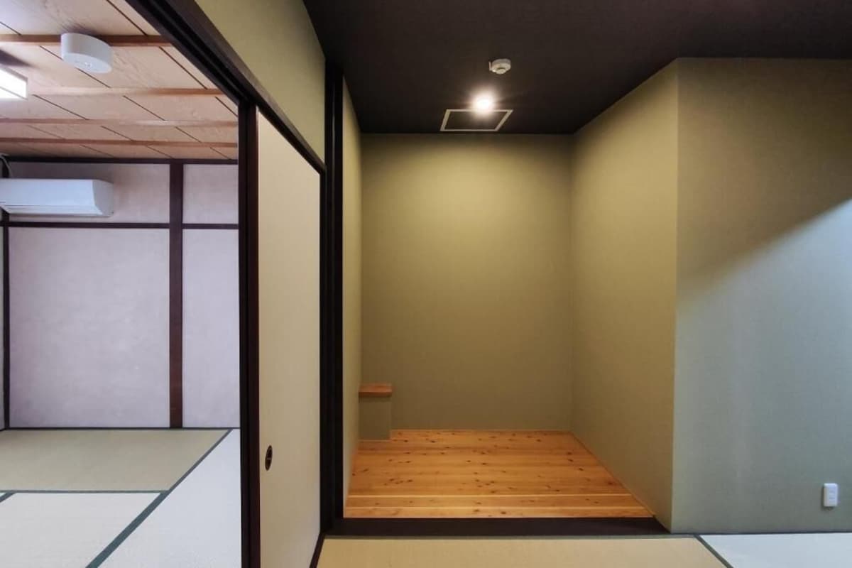 Ein Zimmer mit Tatami-Böden, einer niedrigen Holzplattform und einer Deckenleuchte.