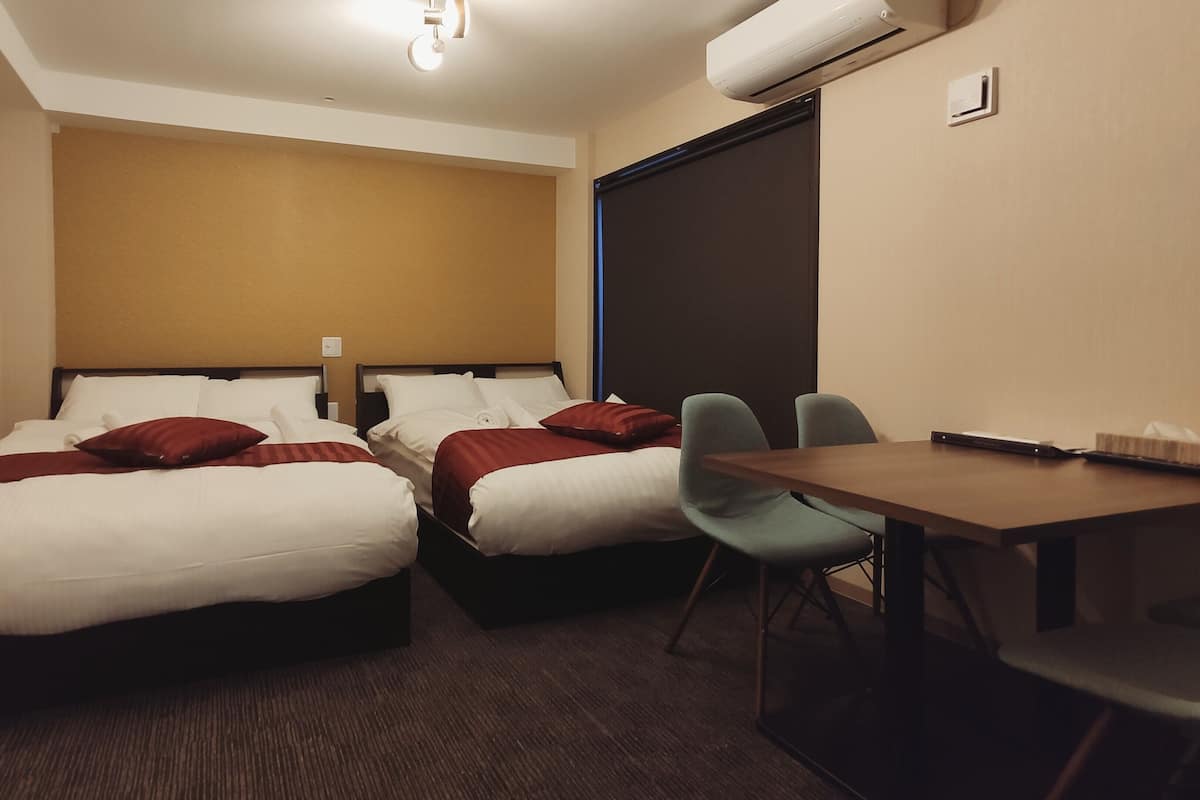 A hotel room with two beds, a desk, and a chair.