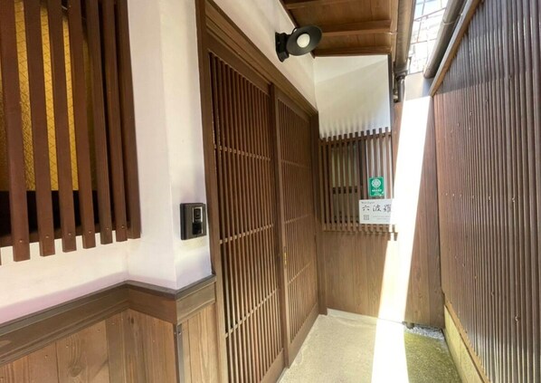 A traditional Japanese interior with sliding wooden doors, a small sign, and a ceiling fan. - West Japan Kyoto Kiyomizu (Kyoto)