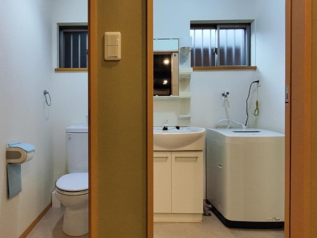 A compact bathroom with a toilet, sink, and washing machine.