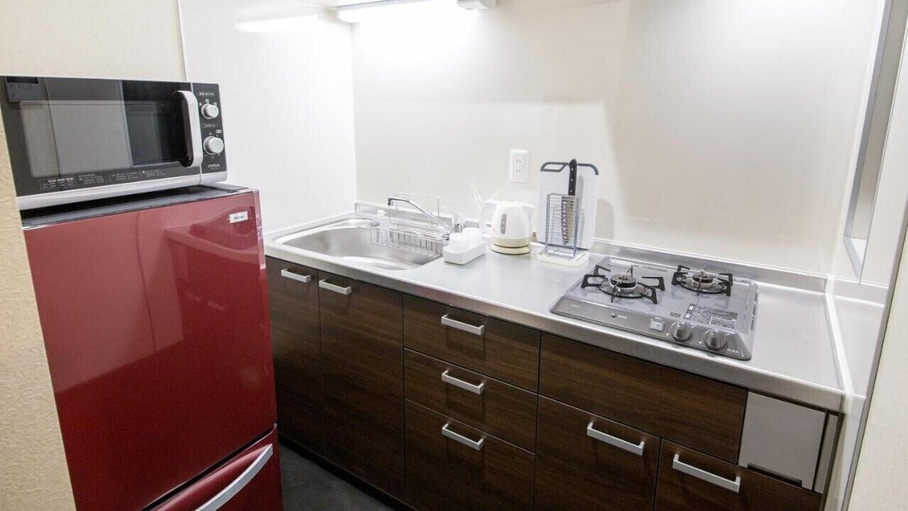 Una kitchenette compacta con microondas, estufa, lavabo y armarios de madera.