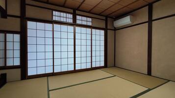 Um quarto japonês tradicional, com tatames, portas deslizantes shoji e um ventilador de teto.