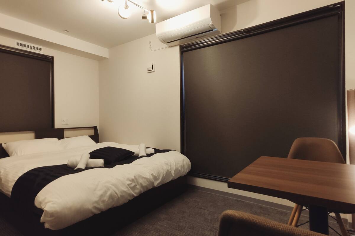 A hotel room with a bed, a desk, and a chair.