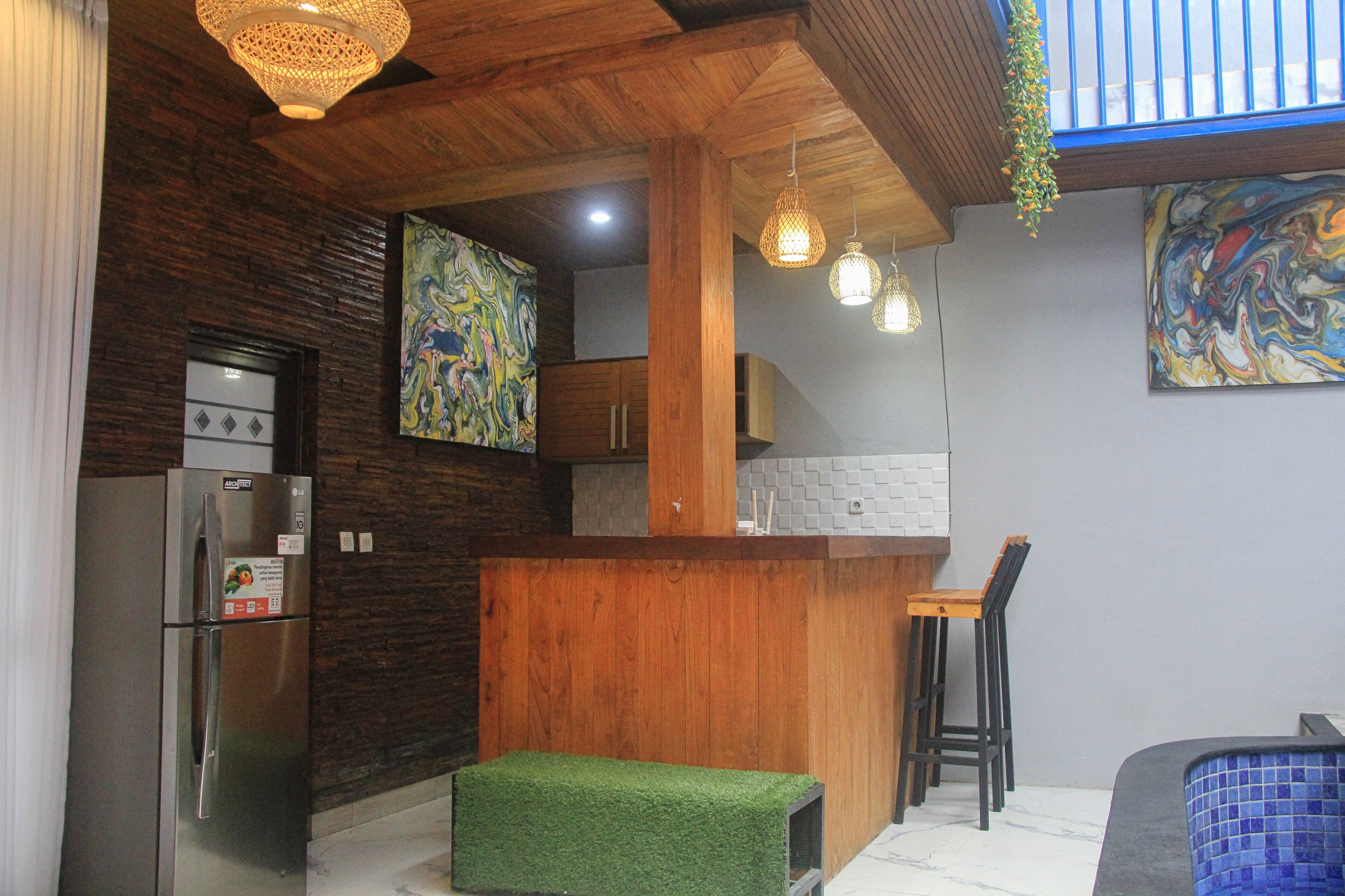 A modern kitchen with a wooden countertop, a stainless steel refrigerator, and a green stool.