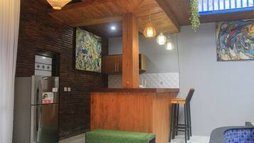A modern kitchen with a wooden countertop, a stainless steel refrigerator, and a green stool.