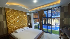 Een moderne hotelkamer met een groot bed, een muur met een geometrisch patroon, uitzicht op een zwembad, en een balkon met een blauwe reling.