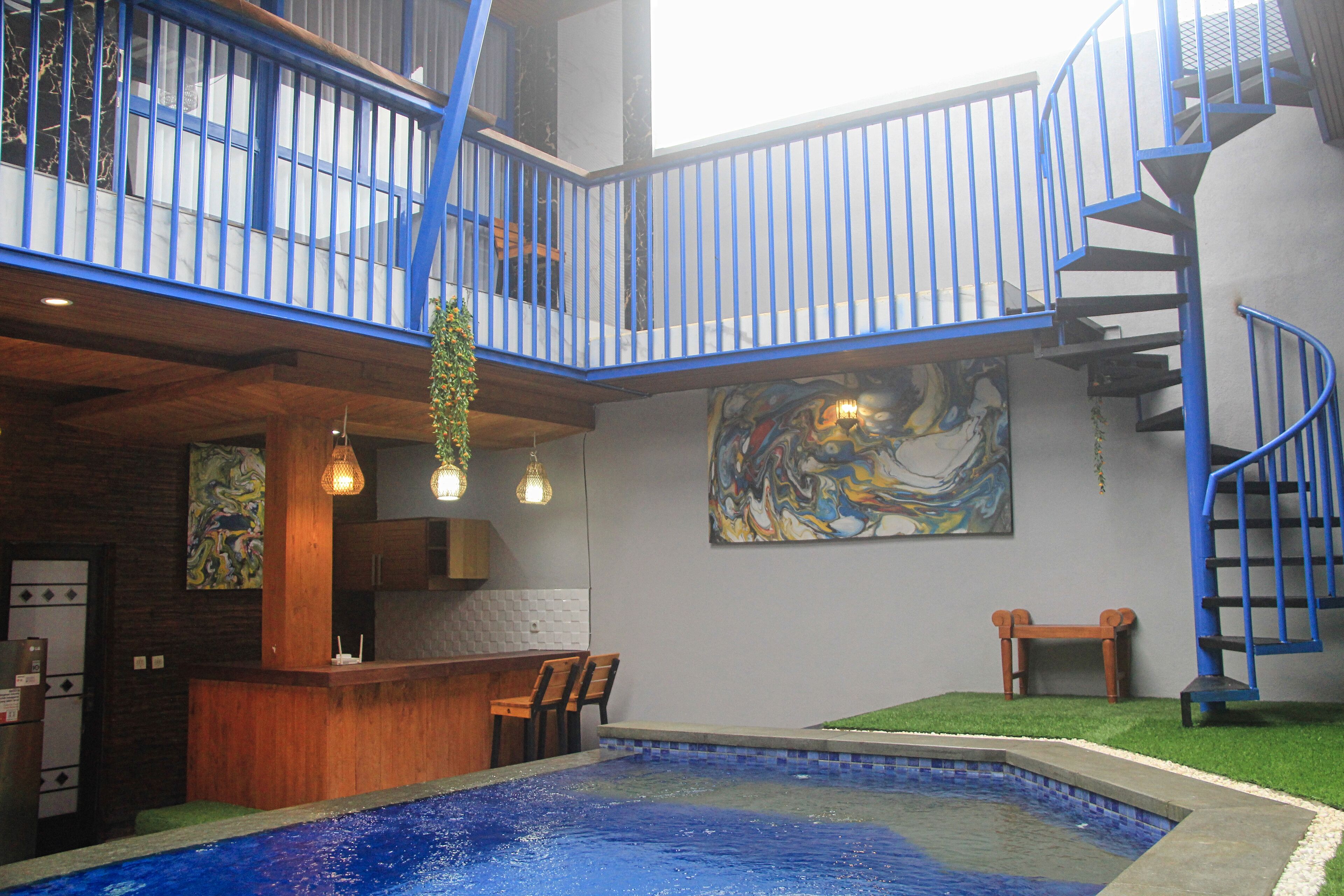 A pool area with a wooden bar and seating, a staircase, and a large abstract painting on the wall.