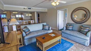 A living room with two grey sofas, a wooden coffee table, and a blue rug.