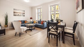 A modern living room with a sofa, armchairs, a dining table with chairs, a coffee table, and a painting on the wall. - Rosen Apartment  (Bergen)