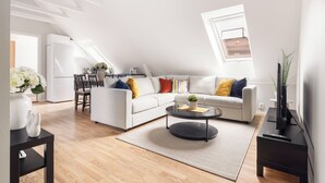 A modern living room with a white sofa, a round coffee table, and a dining area with a white refrigerator. - Rosen Apartment  (Bergen)