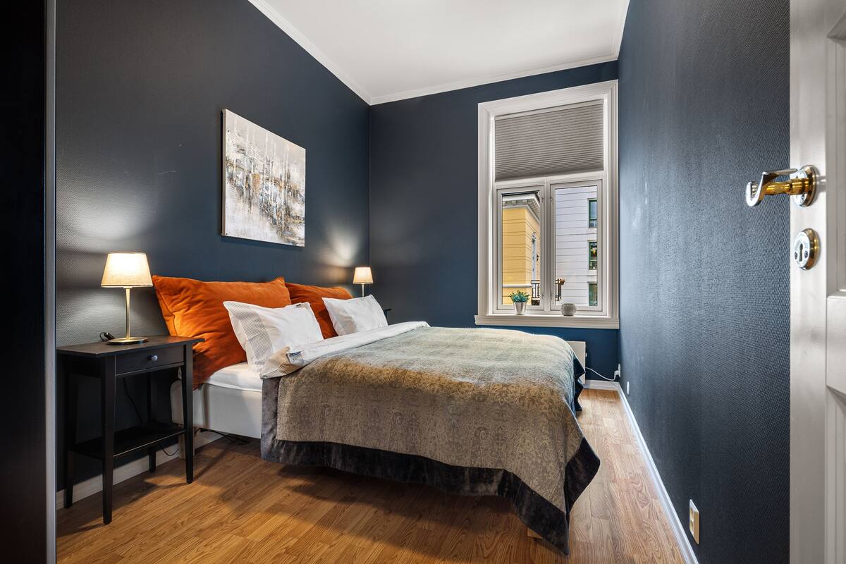 A bedroom with a bed, two bedside tables, a window, and a door.