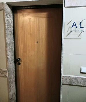 Una porta in legno con una maniglia in metallo, con un cartello appeso alla parete a destra che riporta le lettere 