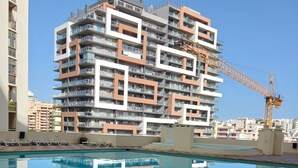 Een modern gebouw met meerdere balkons en een bouwkraan op de achtergrond.