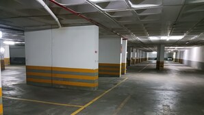 Een meerlaags parkeergarage met betonnen vloeren en muren, aangeduide parkeerplaatsen en structurele kolommen.