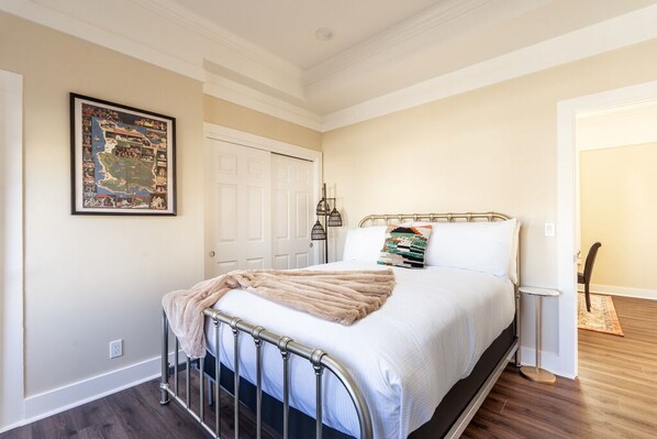 Un dormitorio con una cama, un mapa enmarcado en la pared y una puerta.