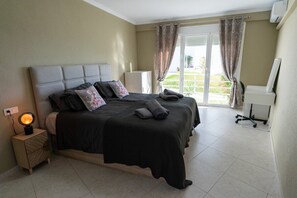 A bedroom with a bed, bedside lamp, and a view of the outdoors.