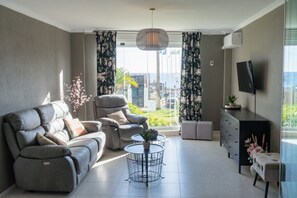 A modern living room with a sofa, a coffee table, and a TV.