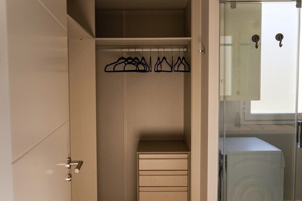 A walk-in closet with a mirrored closet rod and a single drawer unit.