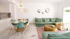 Ein modernes Wohnzimmer mit Essbereich, einem grünen Sofa und einem runden Couchtisch.