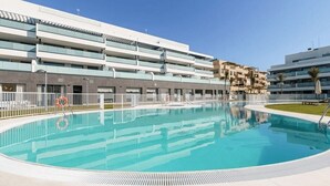 A modern hotel with a central swimming pool, multiple balconies, and a clear sky. - Cala Serena  ·  Beautiful 3 bedroom apartment 850 meters from the beach in La Cala de Mijas (La Cala de Mijas)