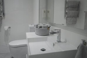 A bathroom with a white sink, a toilet, a mirror, and a towel rack.