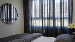 A hotel room with a bed, a round mirror, and a window with sheer curtains. - Cala Serena  ·  Beautiful 3 bedroom apartment 850 meters from the beach in La Cala de Mijas (La Cala de Mijas)