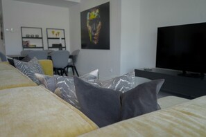 Ein modernes Wohnzimmer mit einer Couch, einem Flachbildfernseher und einem Bild an der Wand.