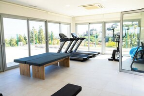 Una palestra con attrezzature per esercizi, una panca e ampie finestre che offrono vista sull'esterno.