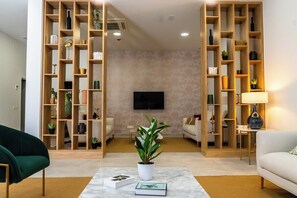 A living room with a TV mounted on the wall, a coffee table with books, and two sofas.