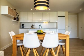 A modern kitchen with white cabinets, a wooden dining table, and white chairs.