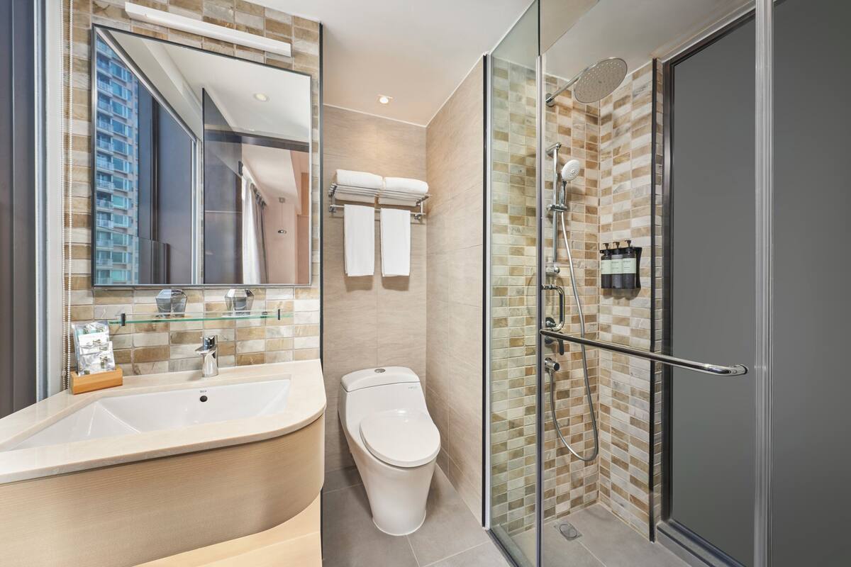 A modern bathroom with a glass-enclosed shower, a large sink, and a toilet.