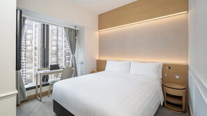 Una habitación de hotel con una cama grande, un escritorio, una silla y una ventana con cortinas.