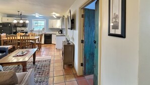 A spacious living area with a dining table and chairs, a kitchen with white cabinets, and a blue door. - Sweet Adobe Convenient to Taos and Taos Ski Valley (Taos)