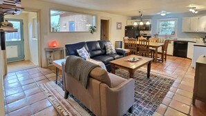 A cozy living room with a sofa, coffee table, and a dining area with chairs and a table. - Sweet Adobe Convenient to Taos and Taos Ski Valley (Taos)