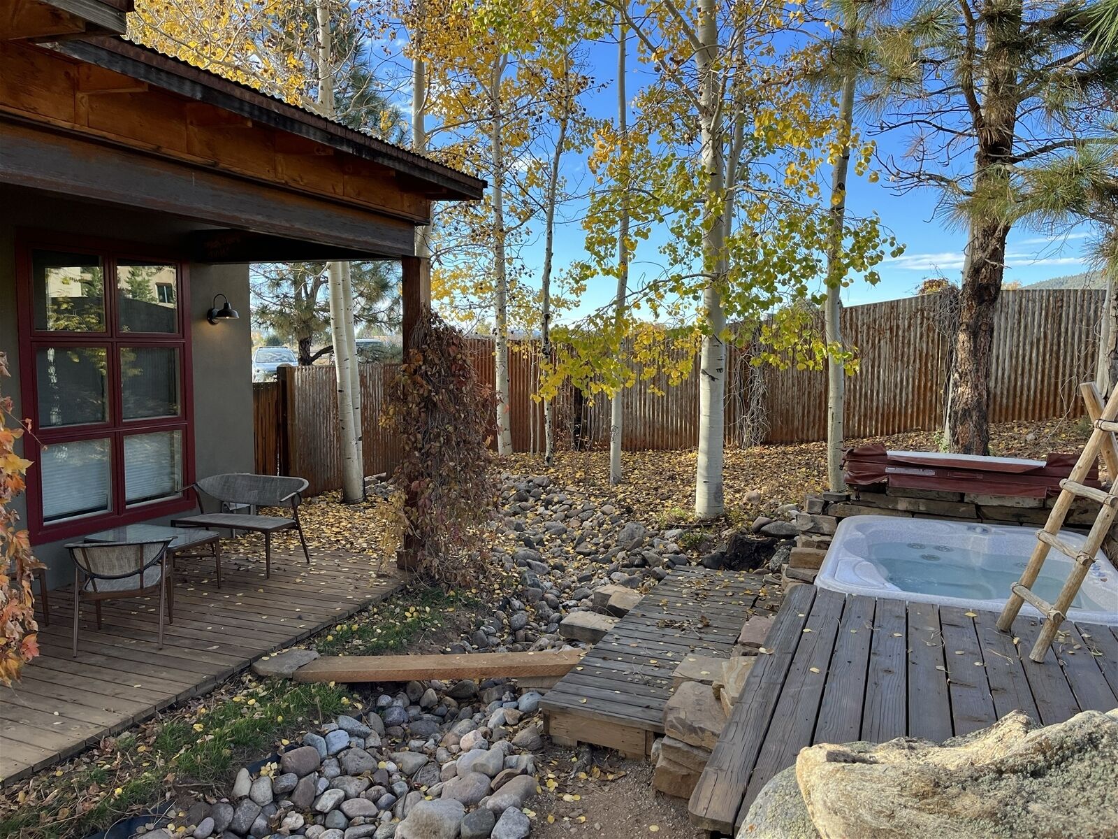 Eine Holzdiele mit Whirlpool, eine Terrasse mit Stühlen und ein Holzzaun im Hintergrund.