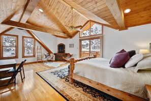 Un dormitorio estilo loft acogedor, con una cama grande, vigas de madera y una chimenea.