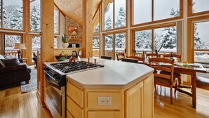 A spacious kitchen with a large island, wooden cabinetry, and a stone fireplace.