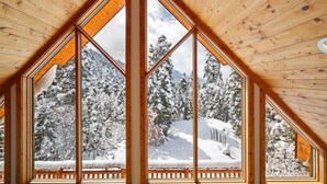 A high-ceilinged room with large windows offering a view of a snow-covered landscape.