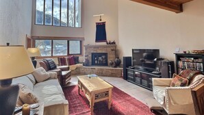 A cozy living room with a fireplace, a TV, and a bookshelf.