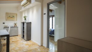 Een modern interieur met een eethoek, een inbouwboekenplank en een glazen deur naar een slaapkamer.