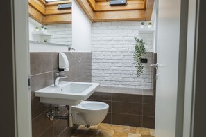 Une salle de bain moderne avec un lavabo blanc, des toilettes et un espace douche.